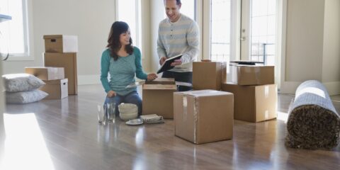 Couple unpacking cardboard boxes in new home